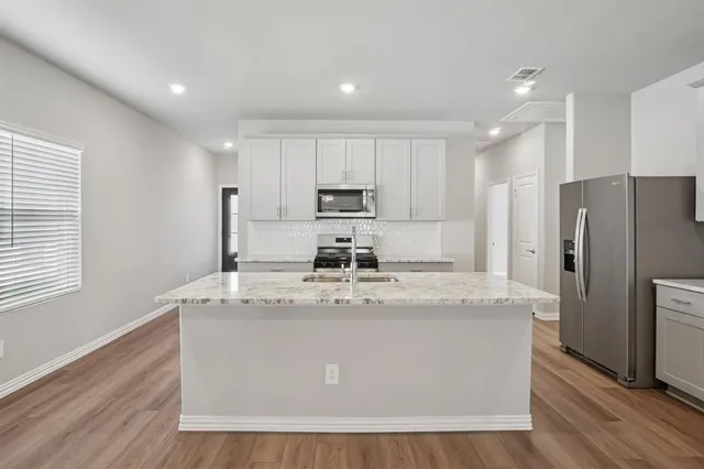 a view of a kitchen with center island and stainless steel appliances
