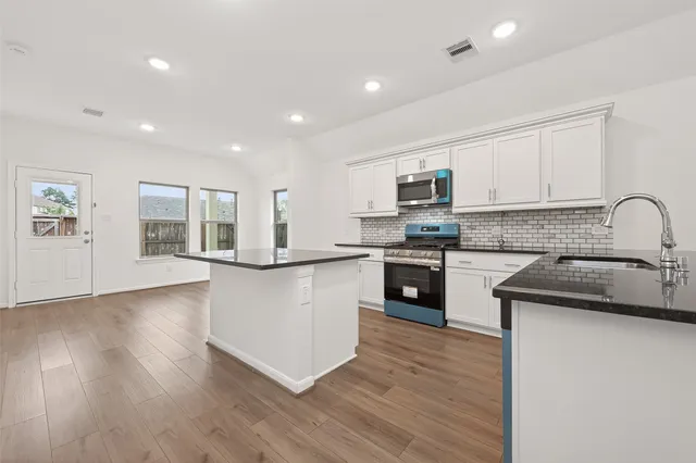 a kitchen with granite countertop white cabinets and black stainless steel appliances