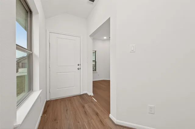 a view of a hallway with wooden floor and entryway