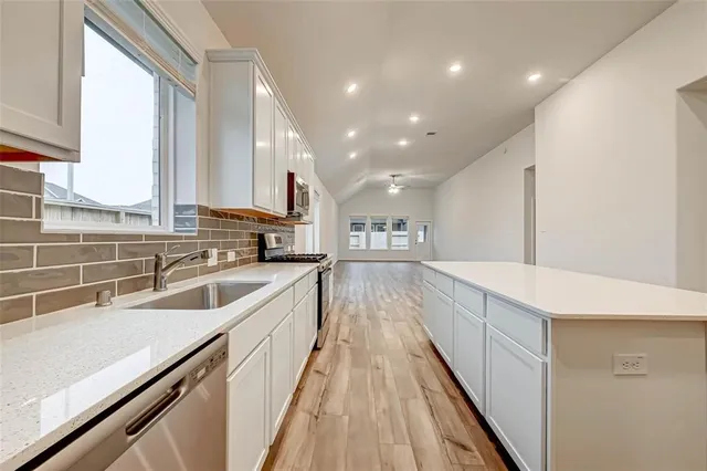 a view of a kitchen with kitchen island a large window a sink and stainless steel appliances