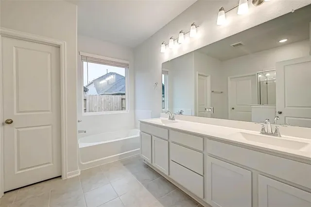 a spacious bathroom with a double vanity sink a mirror and a bathtub
