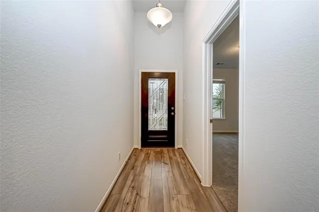 a view of a hallway with wooden floor and a bathroom