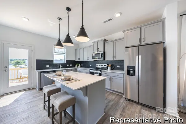 a kitchen that has a refrigerator a stove a sink and a dining table with chairs