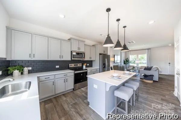 a kitchen with stainless steel appliances kitchen island granite countertop a sink a stove a dining table and chairs
