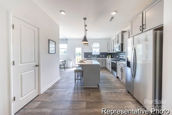 a large kitchen with stainless steel appliances granite countertop a refrigerator a oven a sink and a dining table