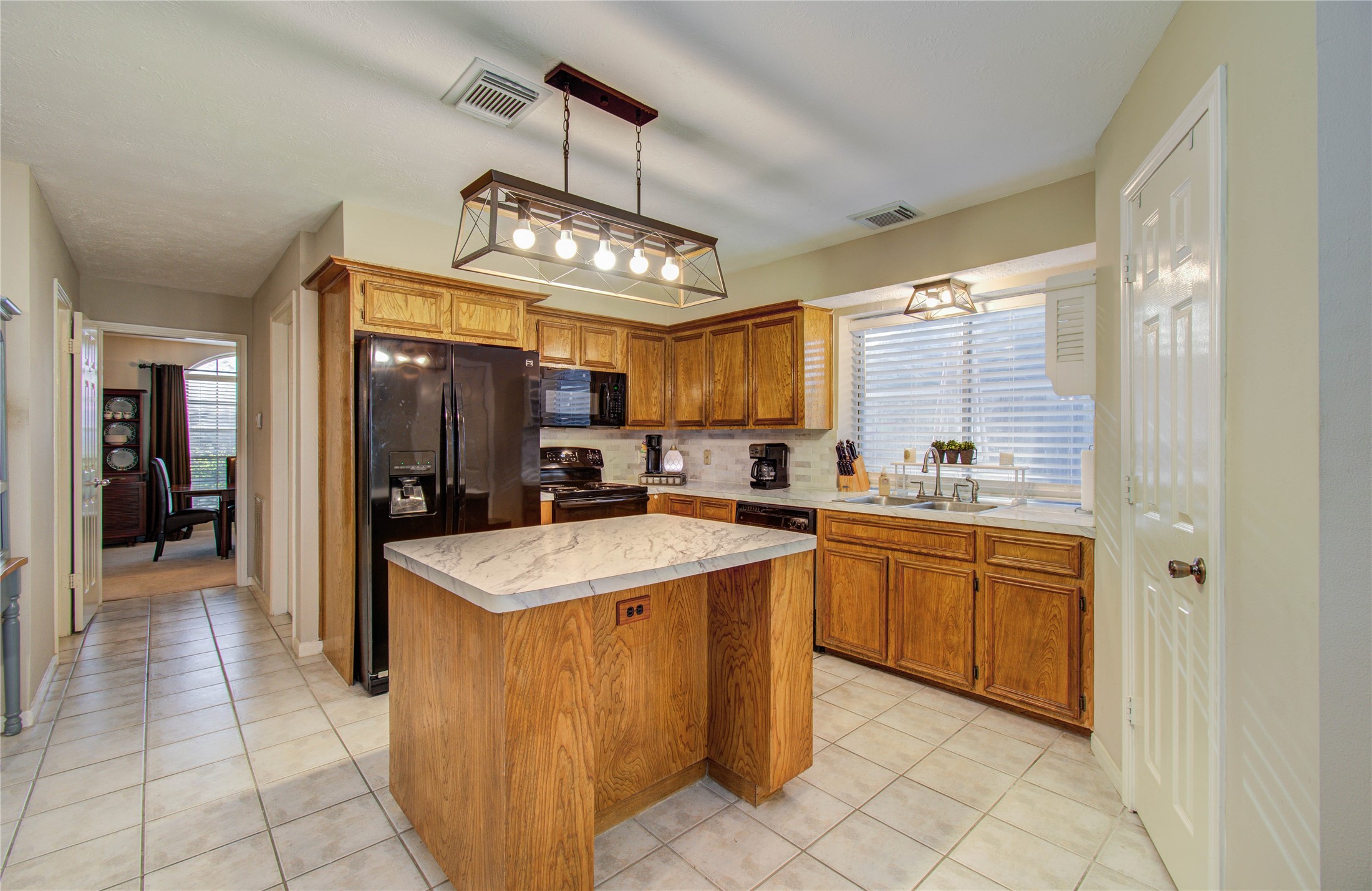 5927 Thom Road Humble, TX 77346 - Photo 13 of 50 The kitchen and breakfast area are filled with natural light and open seamlessly to the living room, offering lovely views of the back patio—perfect for gathering with family and friends.