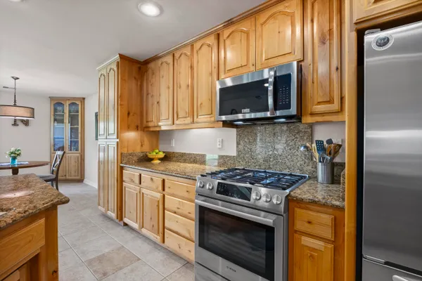 a kitchen with stainless steel appliances granite countertop a stove a sink and a microwave