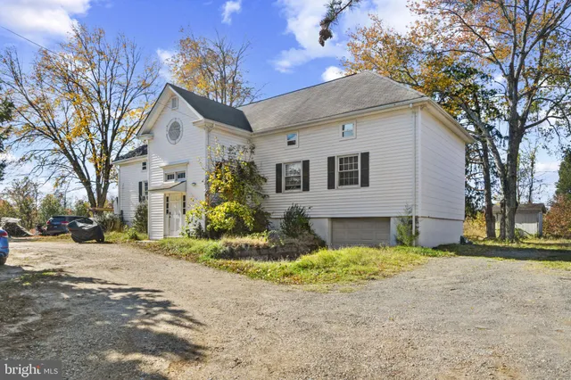 a view of a white house with a large trees