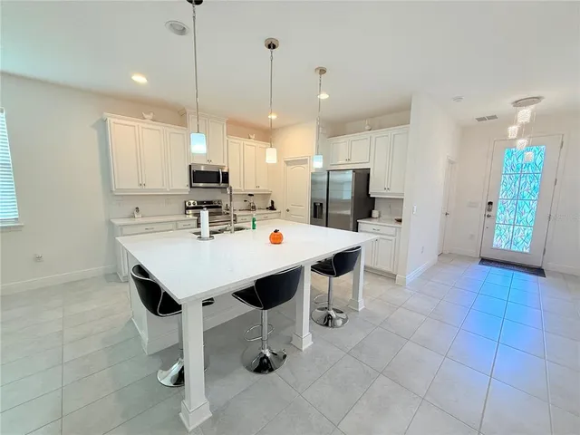 a kitchen with stainless steel appliances kitchen island granite countertop a sink refrigerator and cabinets