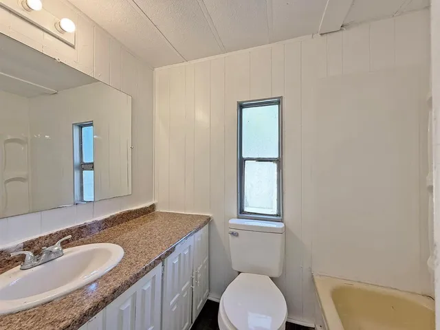 a bathroom with a granite countertop sink toilet and a mirror