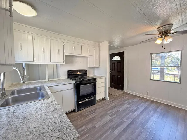 a kitchen with granite countertop a stove a sink and a refrigerator