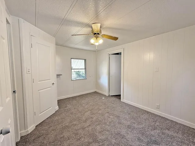 an empty room with ceiling fan and window