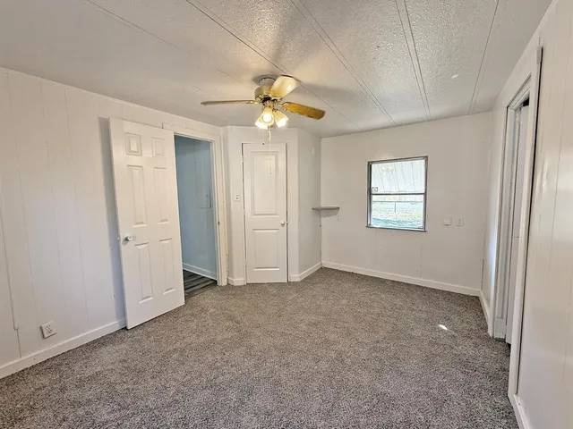 an empty room with windows and chandelier fan