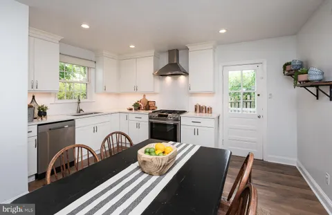 a kitchen with stainless steel appliances granite countertop a stove a sink a refrigerator and a stove with wooden floor