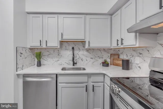 a kitchen with stainless steel appliances granite countertop a sink a stove and white cabinets