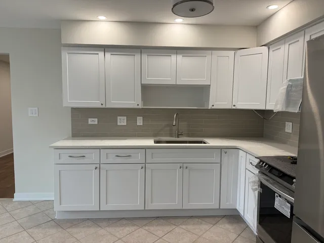 a kitchen with white cabinets and sink