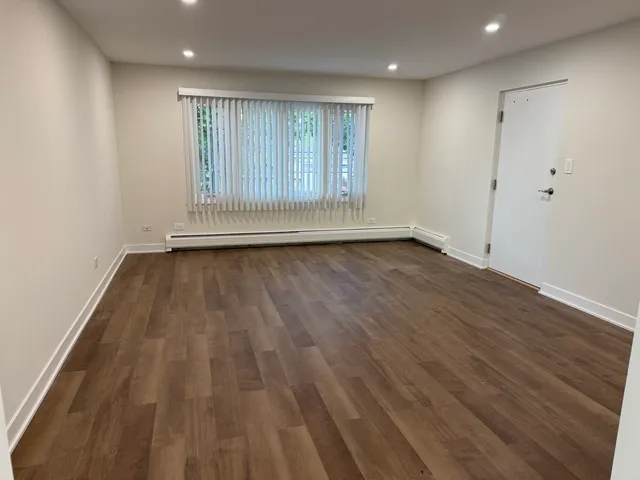 a view of an empty room with wooden floor and window