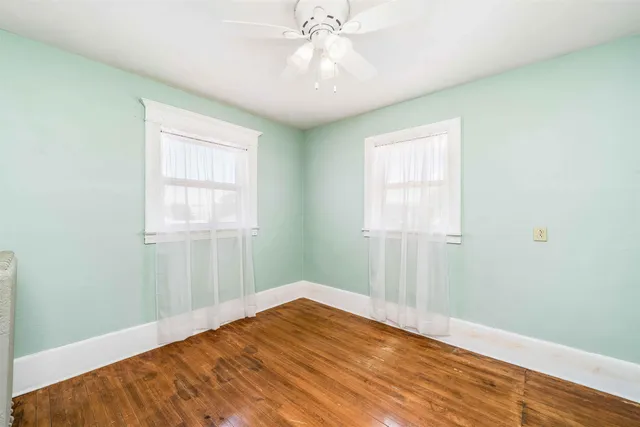 an empty room with chandelier fan and windows