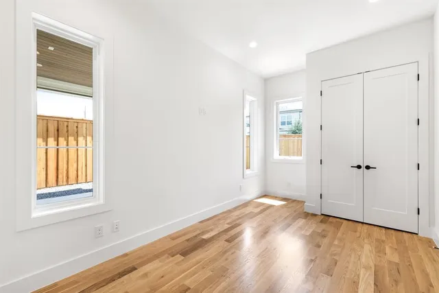 a view of an empty room with wooden floor fireplace and a window