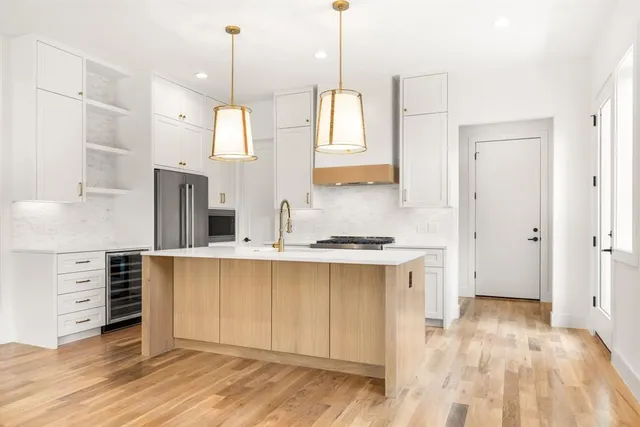 a kitchen with stainless steel appliances a stove a sink and white cabinets with wooden floor