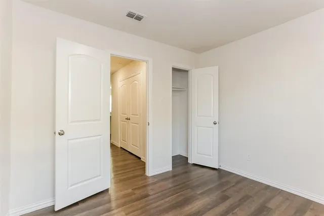 a view of an empty room with wooden floor and closet