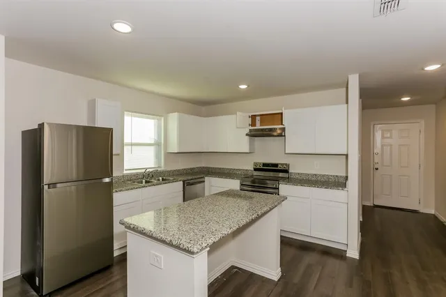 a kitchen with a refrigerator a stove a microwave and wooden floor