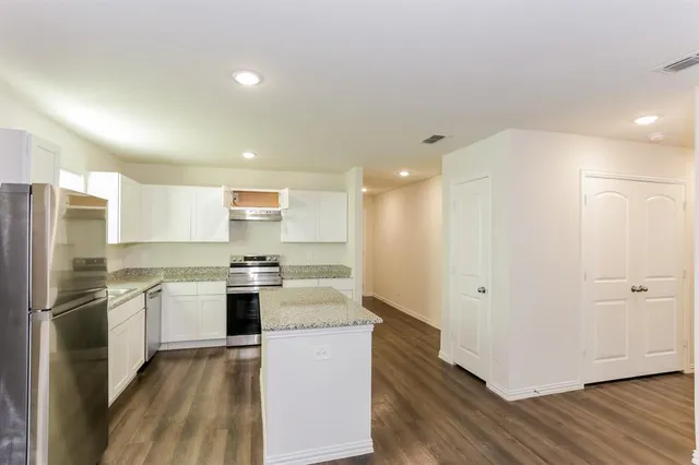 a kitchen with stainless steel appliances granite countertop a refrigerator a stove and a sink