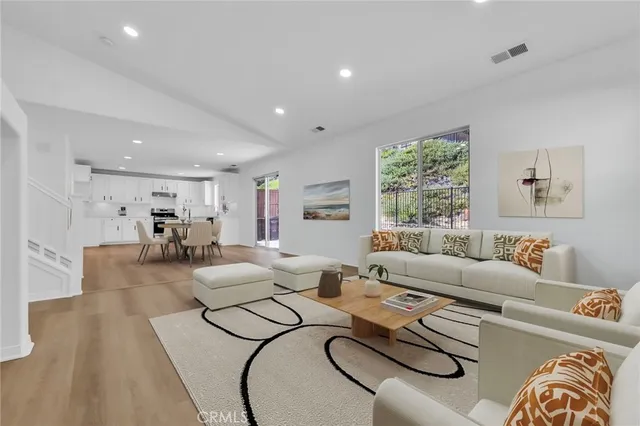 a living room with furniture kitchen view and a large window