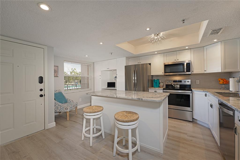 6501 Stone River Road, Unit 205 Bradenton, FL 34203 - Photo 13 of 50 a kitchen with stainless steel appliances granite countertop a stove a sink a microwave a refrigerator white cabinets and chairs with wooden floor