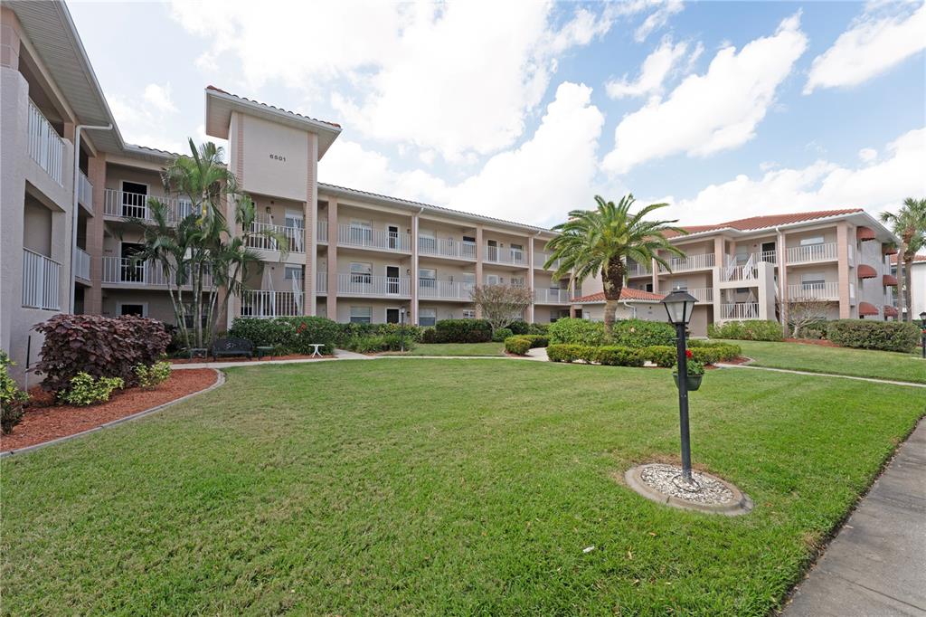 6501 Stone River Road, Unit 205 Bradenton, FL 34203 - Photo 2 of 50 a garden with tall buildings in the background