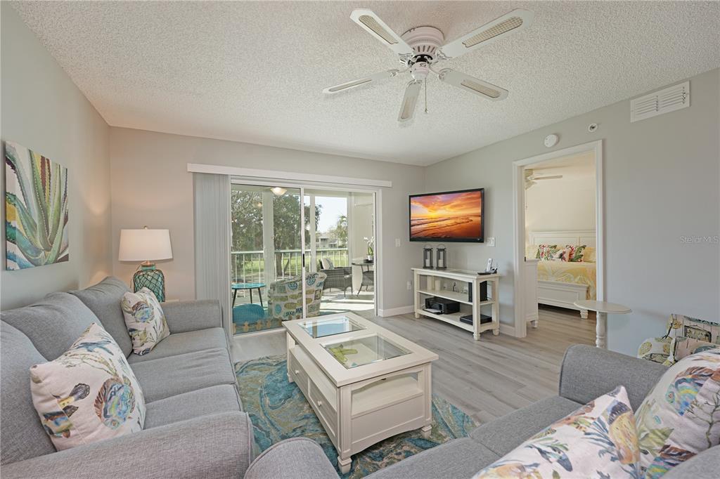 6501 Stone River Road, Unit 205 Bradenton, FL 34203 - Photo 9 of 50 a living room with furniture a flat screen tv and a large window