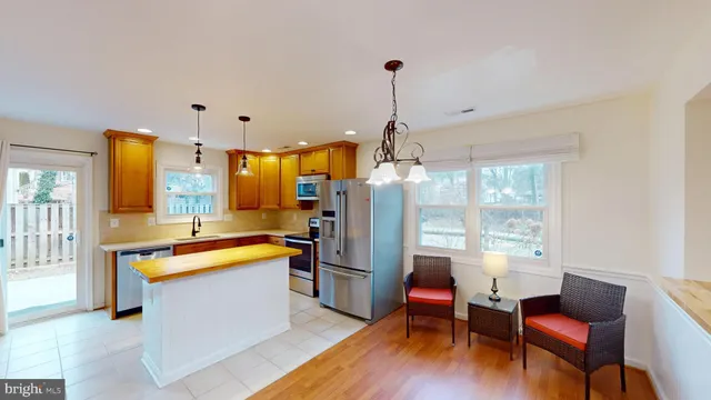 a kitchen with stainless steel appliances kitchen island granite countertop a refrigerator a stove and a dining table with wooden floor