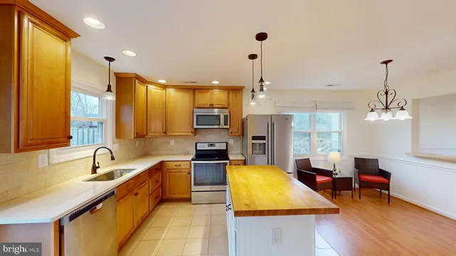 a large kitchen with kitchen island a large window a sink and stainless steel appliances
