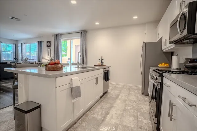 a kitchen with stainless steel appliances granite countertop a stove top oven a sink dishwasher and white cabinets with wooden floor