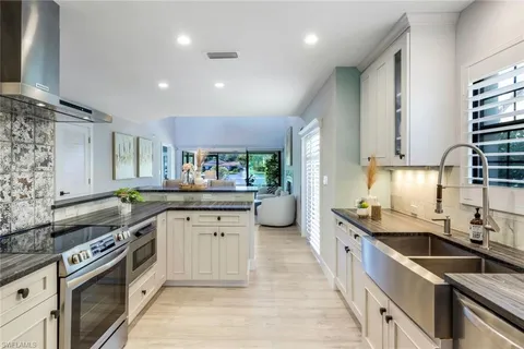 a large kitchen with stainless steel appliances a sink stove and cabinets