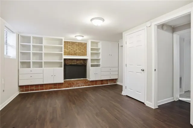an empty room with wooden floor closet and windows