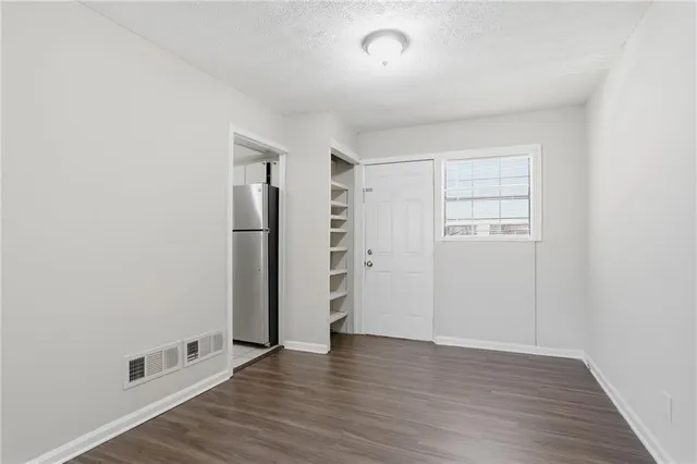 an empty room with wooden floor & closet and windows