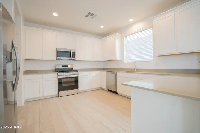 a kitchen with cabinets stainless steel appliances and a sink