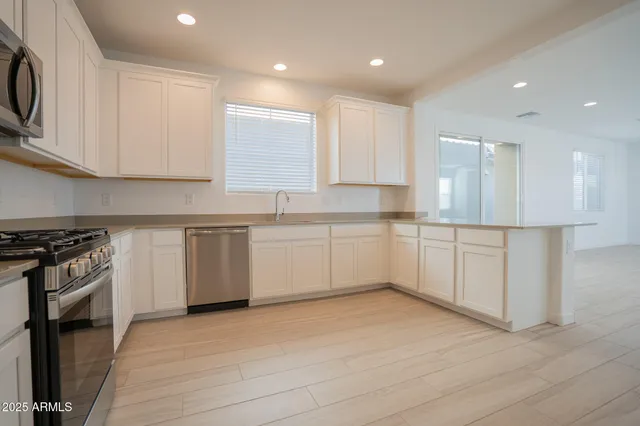 a kitchen with a sink white cabinets and stainless steel appliances