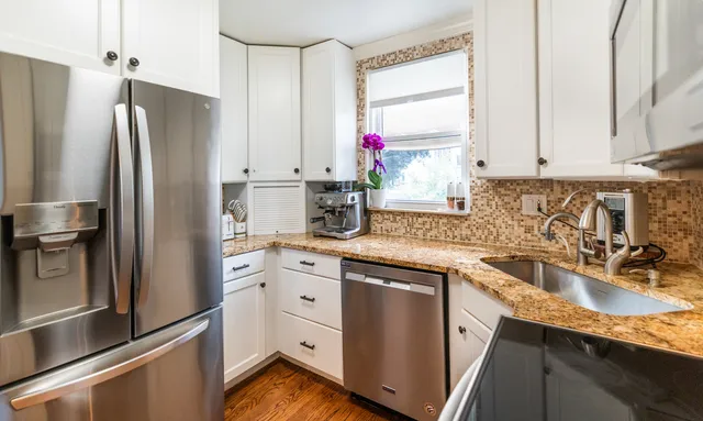 a kitchen with granite countertop a refrigerator sink and cabinets