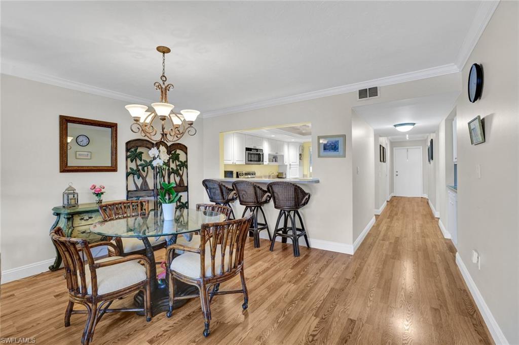 855 Ketch Drive, Unit 206 Naples, FL 34103 - Photo 6 of 17 Dining area with suspended lighting, light wood-type flooring, and crown molding