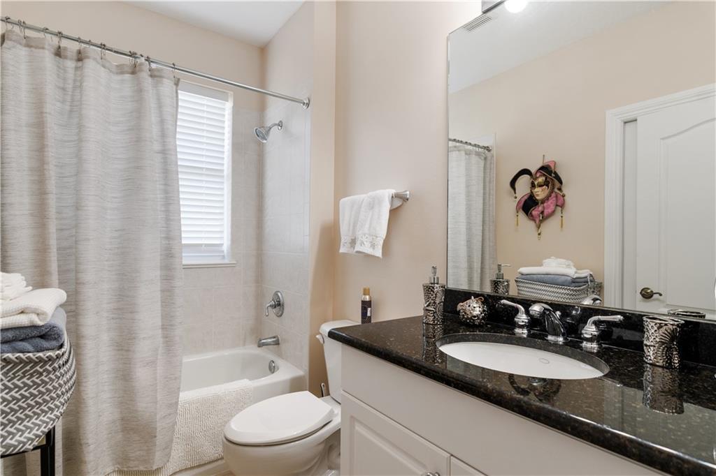 1915 Bridgepointe Circle, Unit 41 Vero Beach, FL 32967 - Photo 24 of 36 a bathroom with a granite countertop sink toilet a mirror a bathtub and shower