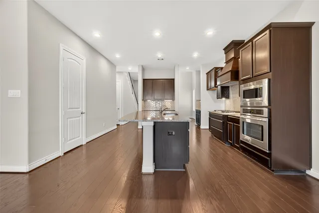 a kitchen with stainless steel appliances granite countertop a refrigerator a stove and a wooden floors