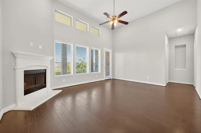 an empty room with wooden floor fireplace and windows