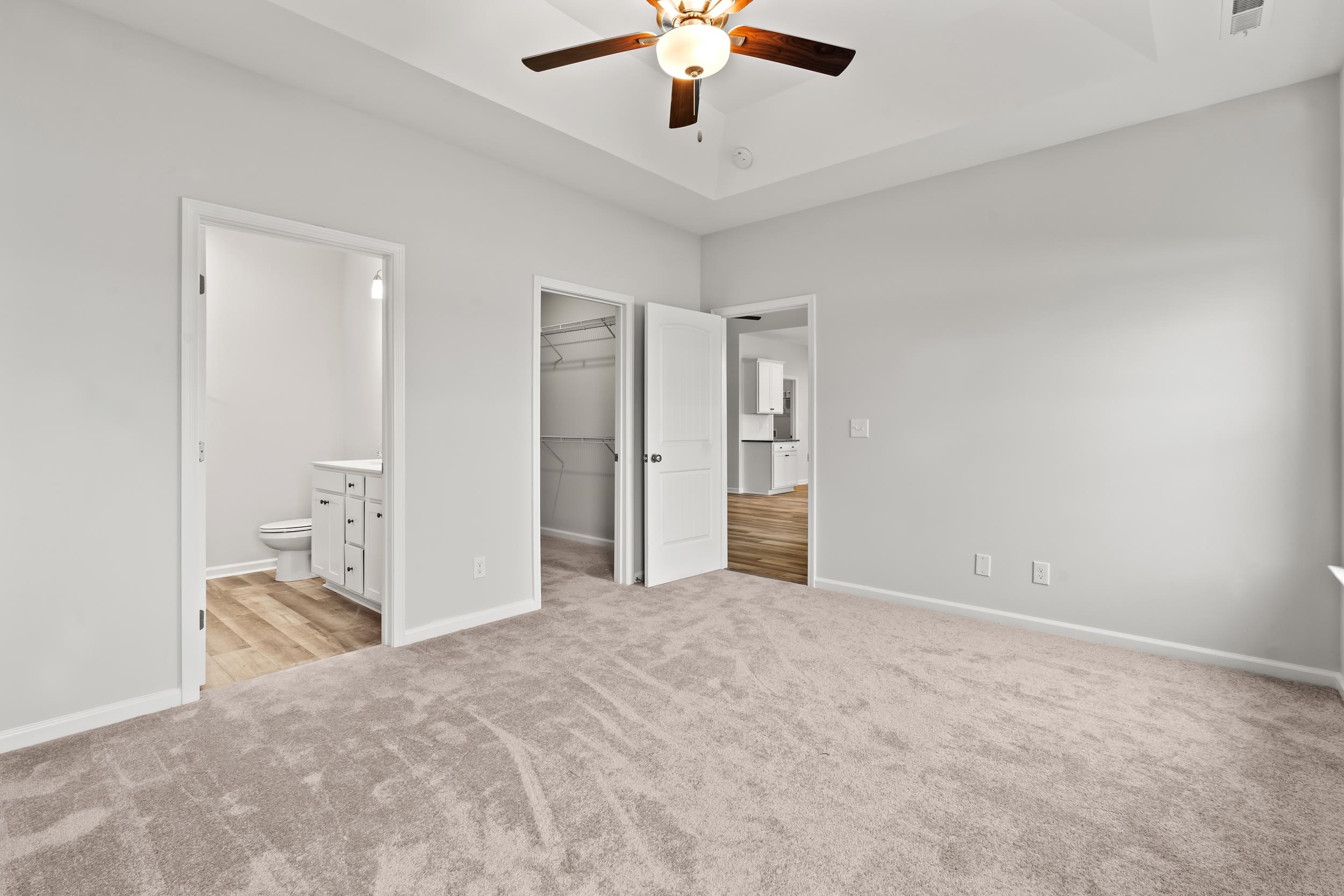 231 Stillbrook Drive Longs, SC 29568 - Photo 18 of 38 Unfurnished bedroom with a walk in closet, ceiling fan, connected bathroom, and light carpet