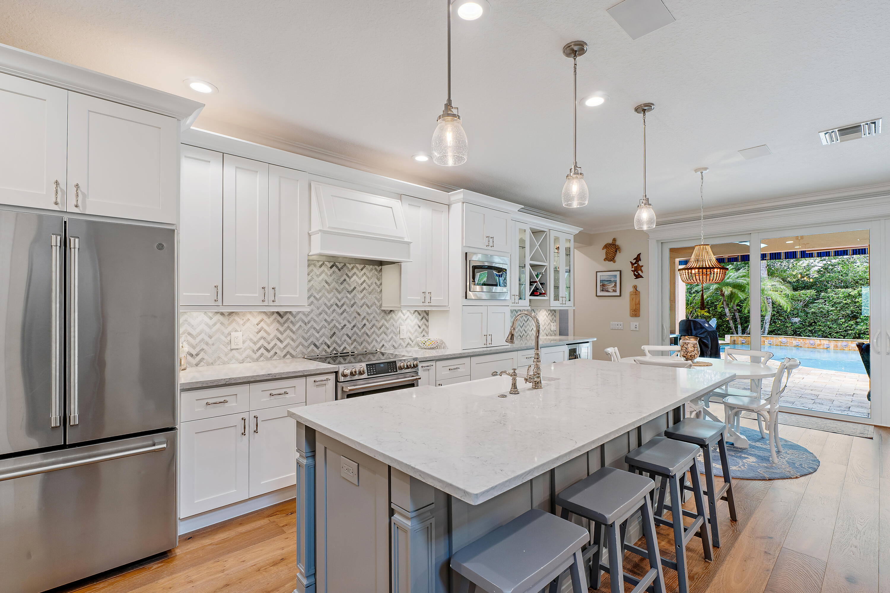 338 Caravelle Drive Jupiter, FL 33458 - Photo 19 of 97 a kitchen with stainless steel appliances granite countertop a sink a stove a refrigerator and island with wooden floor