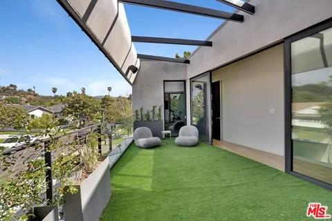 a view of a swimming pool and lounge chairs in back of the house