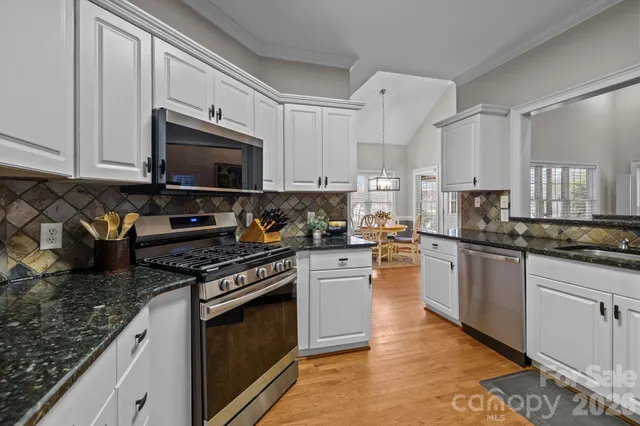 a kitchen with stainless steel appliances granite countertop a stove a sink and a microwave