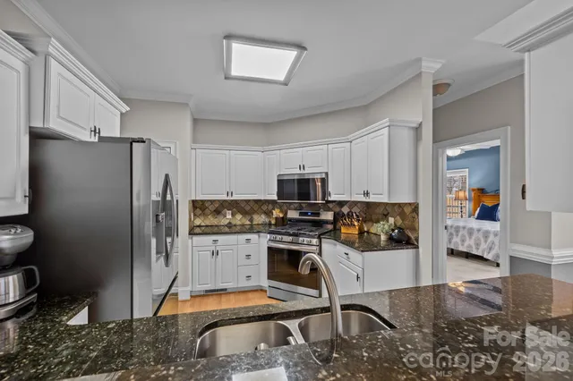 a kitchen with stainless steel appliances granite countertop a refrigerator stove top oven and sink