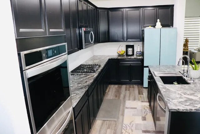 a kitchen with granite countertop a refrigerator stove and oven